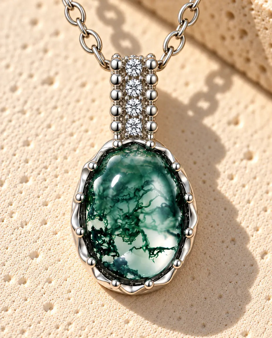 Oval Moss Agate Necklace in 925 Sterling Silver - lying on a cream textured surface beside a travertine block