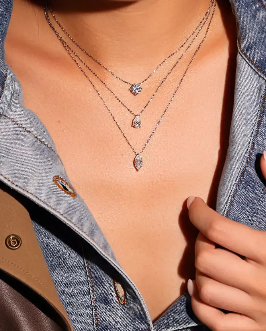 1 ct Pear Moissanite Necklace in 925 Sterling Silver - worn on a model, layered with other necklaces