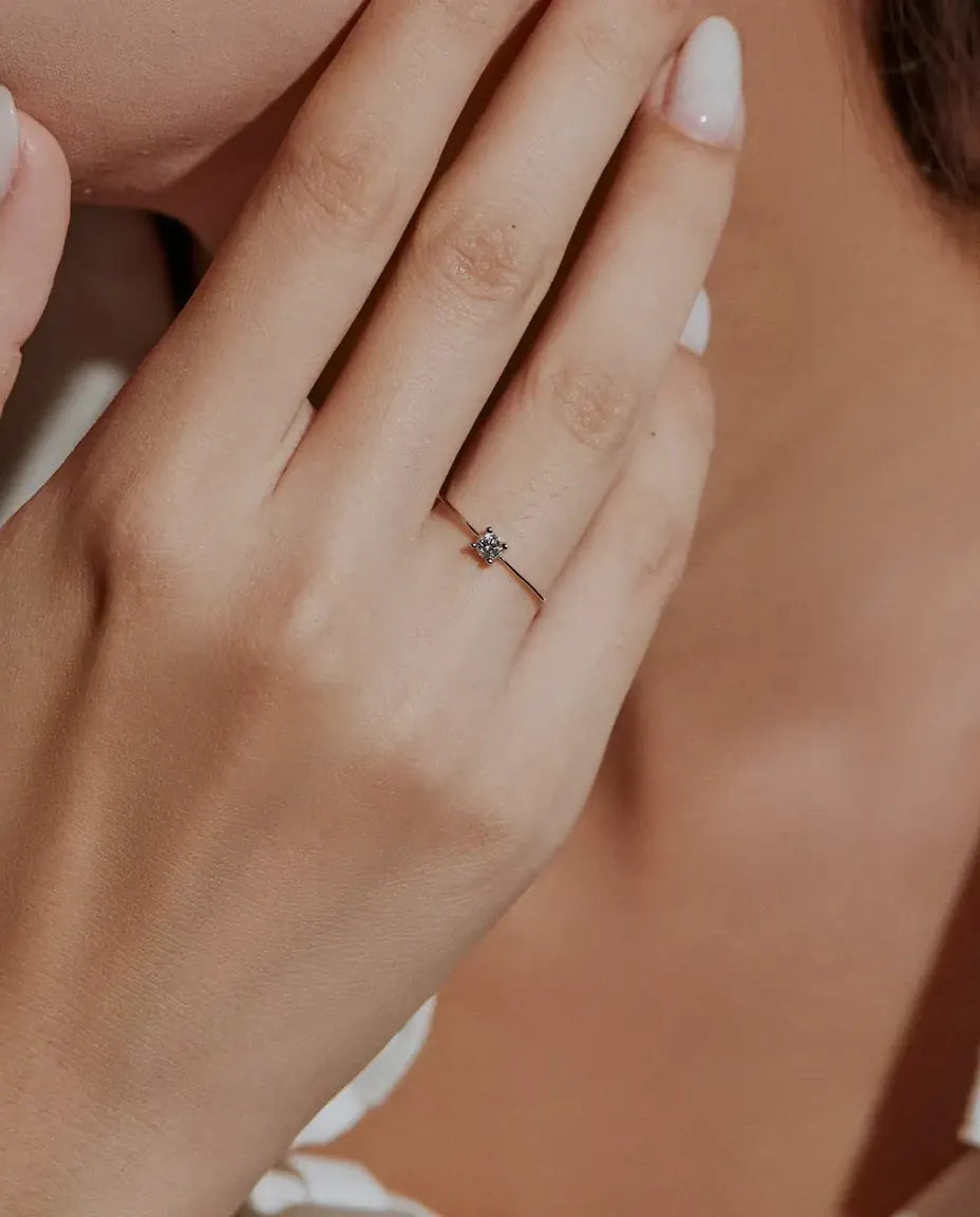 Dainty Moissanite Solitaire Ring in 925 Sterling Silver - worn on a model with her hands near her face