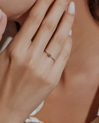 Dainty Moissanite Solitaire Ring in 925 Sterling Silver - worn on a model with her hands near her face