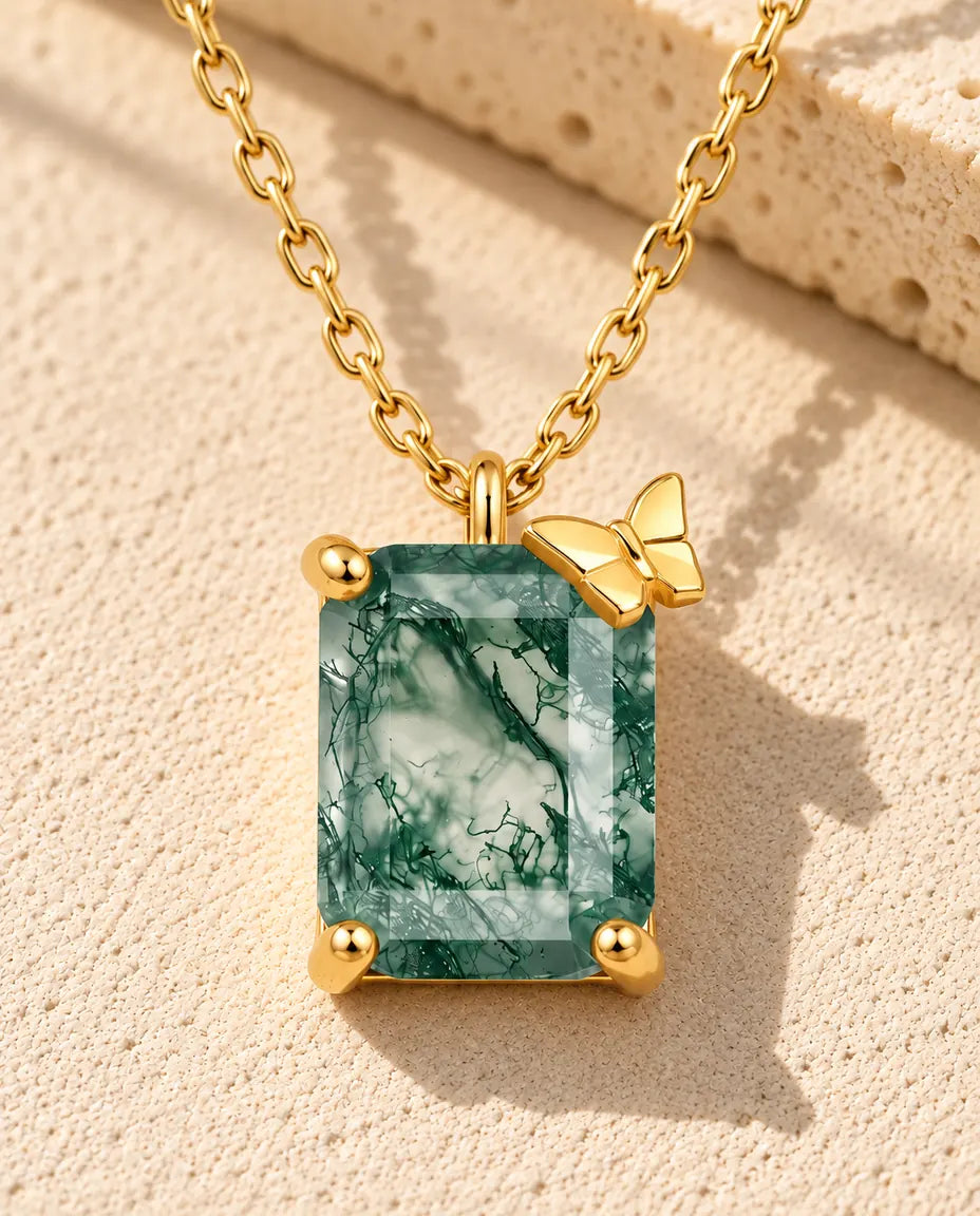 Emerald Cut Moss Agate Necklace in 10K Gold Plated 925 Sterling Silver - lying on a cream textured surface beside a travertine block