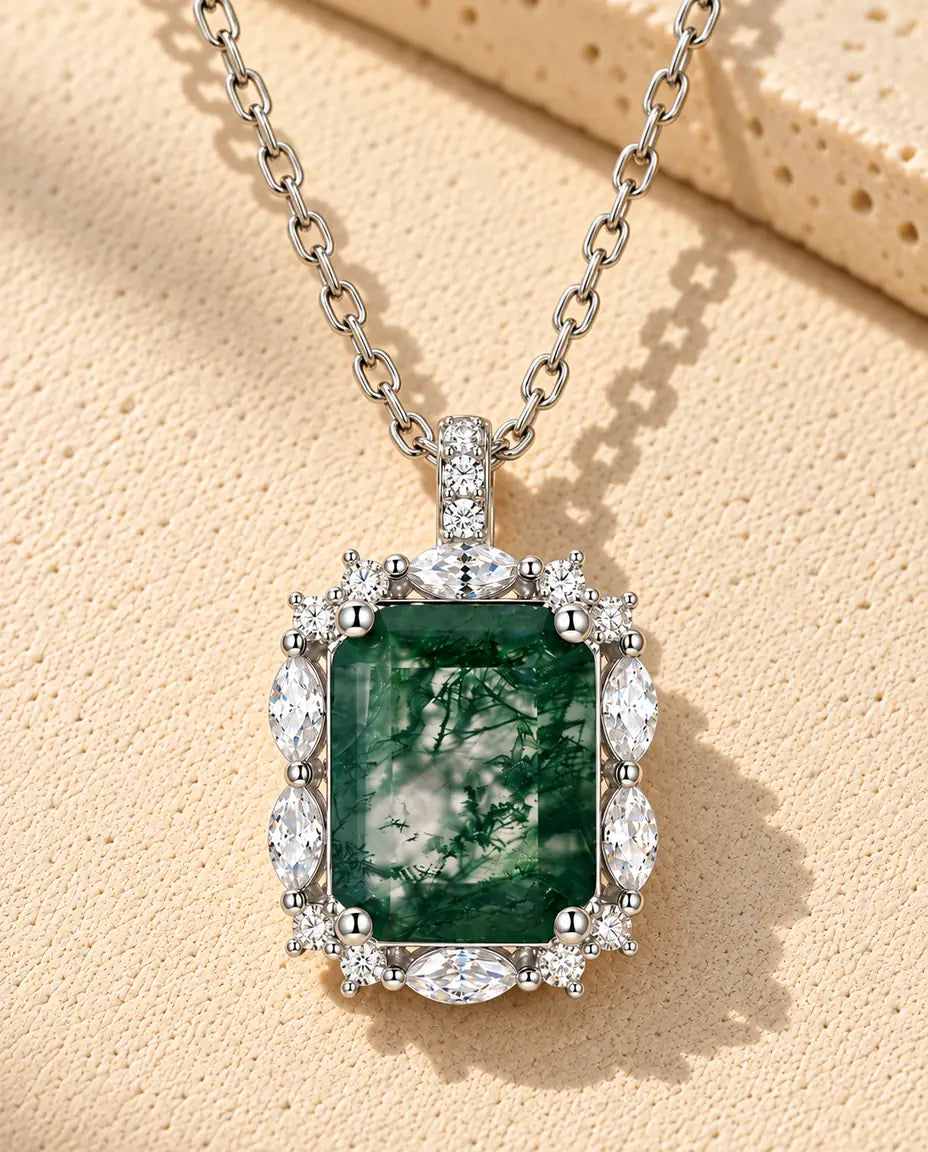Emerald Cut Moss Agate Cluster Necklace in 925 Sterling Silver - lying on a cream textured surface beside a travertine block