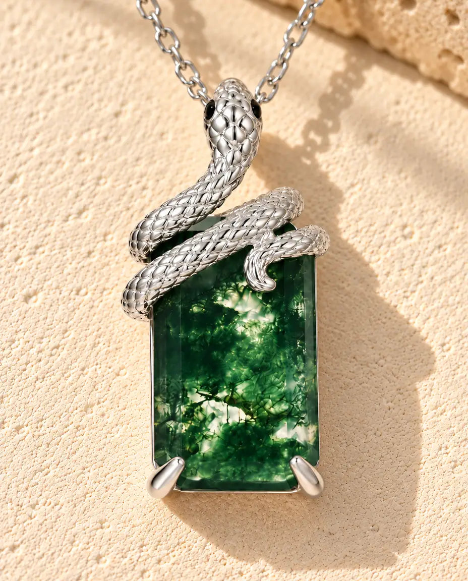 Moss Agate Snake Necklace in 925 Sterling Silver - lying on a cream textured surface beside a travertine block