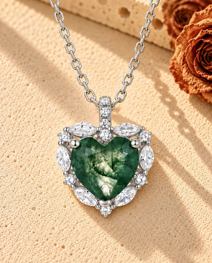 Heart Moss Agate Halo Necklace in 925 Sterling Silver - lying on a cream textured surface beside a travertine block