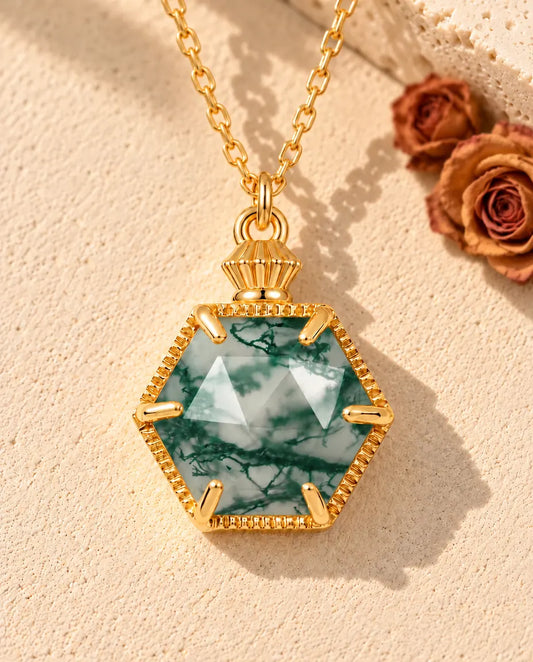 Hexagon Moss Agate Necklace in 10K Gold Plated 925 Sterling Silver - lying on a cream textured surface beside a travertine block