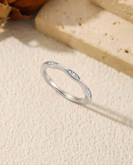 Moissanite Wave Ring in 925 Sterling Silver - standing upright on a cream textured surface