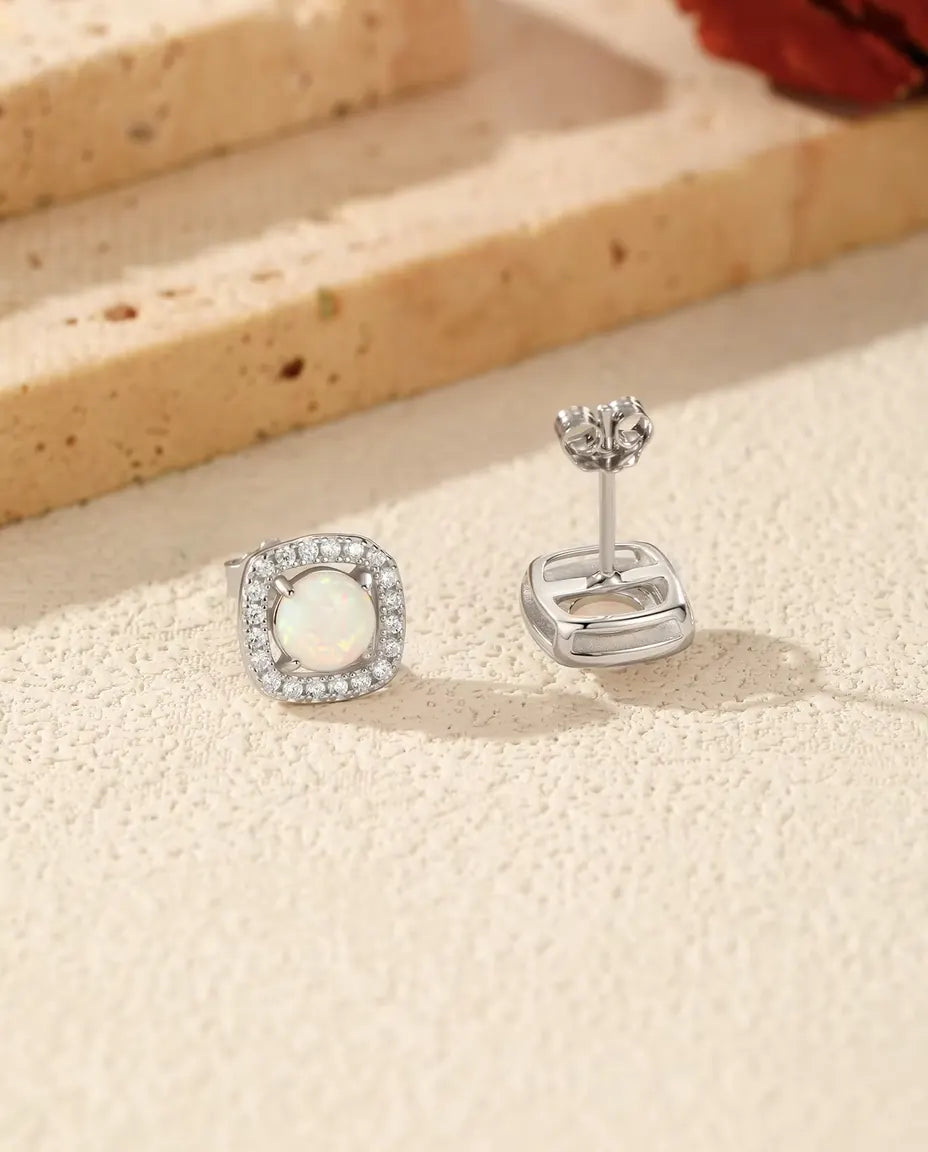 Opal Halo Stud Earrings in 925 Sterling Silver - the pair on a cream stone surface
