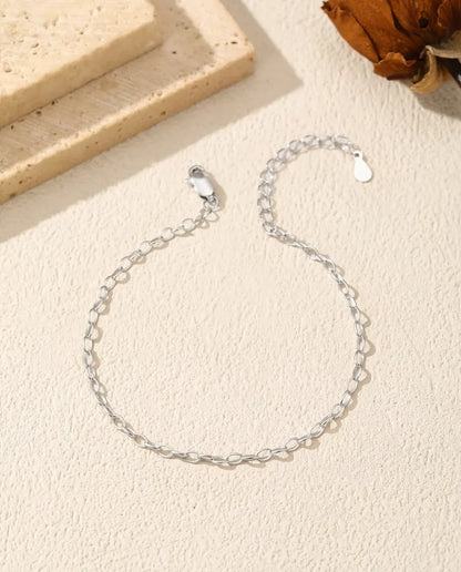 Oval Link Chain Bracelet in 925 Sterling Silver - laid loosely on a cream surface with the clasp and extender