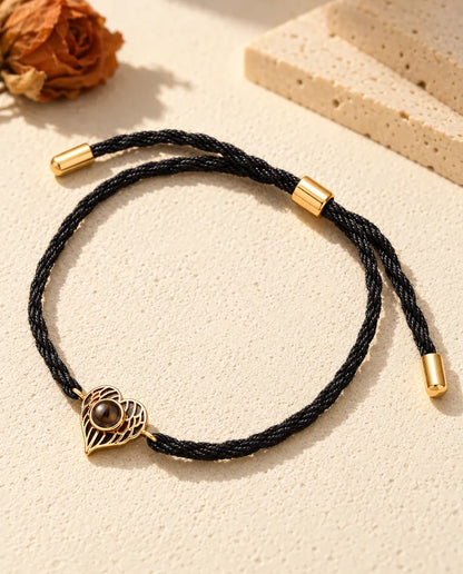 Gold tone angel wing heart memorial bracelet on a twisted black rope cord with slider and end caps