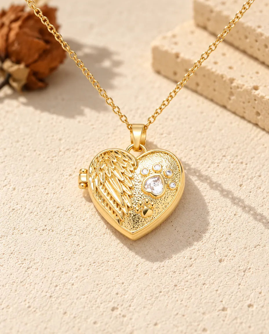 Front view of the gold tone angel wing paw print heart locket showing the lid design and side hinge