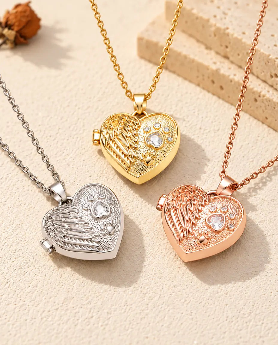 Three colours of the angel wing paw print heart photo locket necklace arranged on plaster