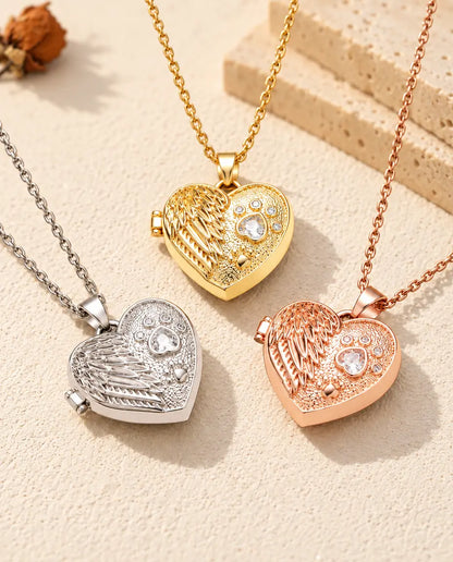 Three colours of the angel wing paw print heart photo locket necklace arranged on plaster