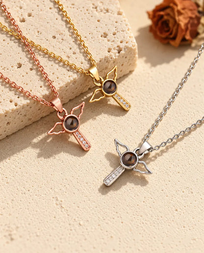Rose gold tone, gold tone and silver tone winged cross pendants on travertine