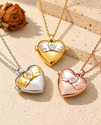 Three colours of the angel wings heart photo locket necklace arranged on plaster