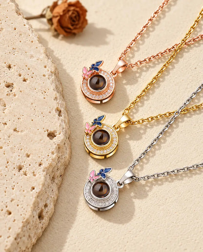 Rose gold tone, gold tone and silver tone butterfly circle pendants stacked beside a travertine slab