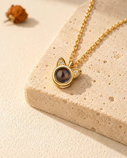 Personalised gold tone cat ear photo projection necklace on a travertine block
