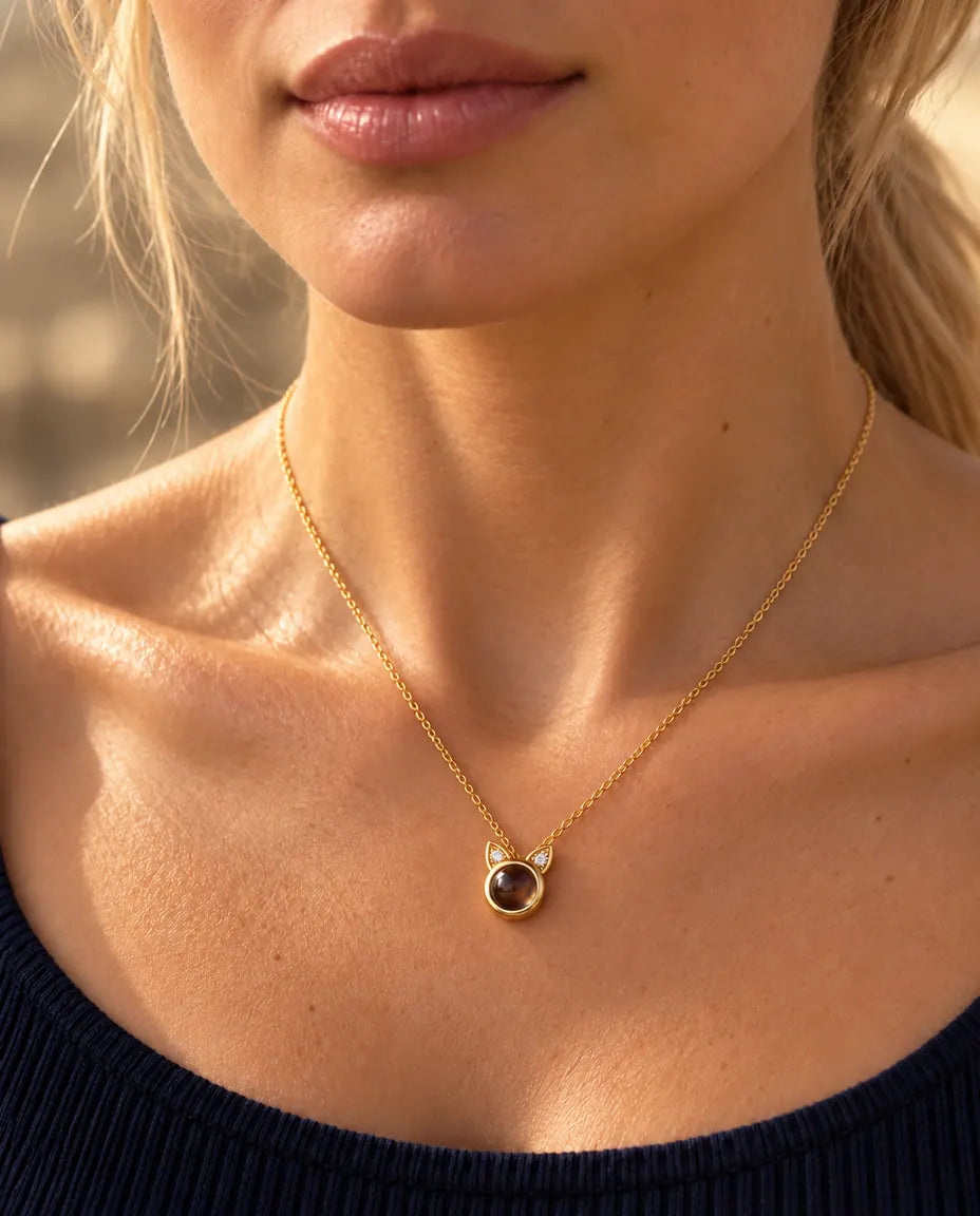 Woman in a navy top wearing the tiny gold tone cat ear projection necklace