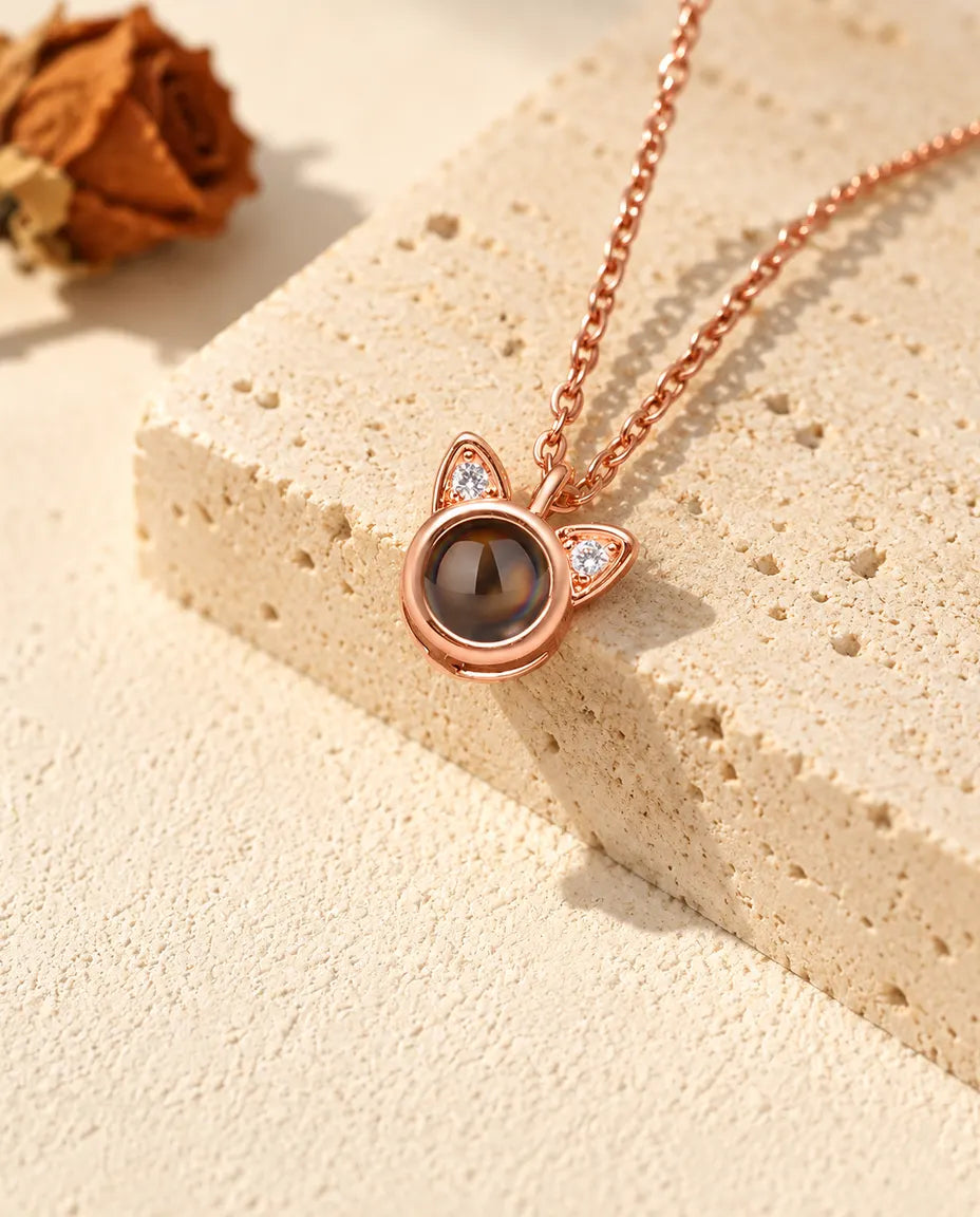 Rose gold tone cat ear projection necklace hanging over travertine