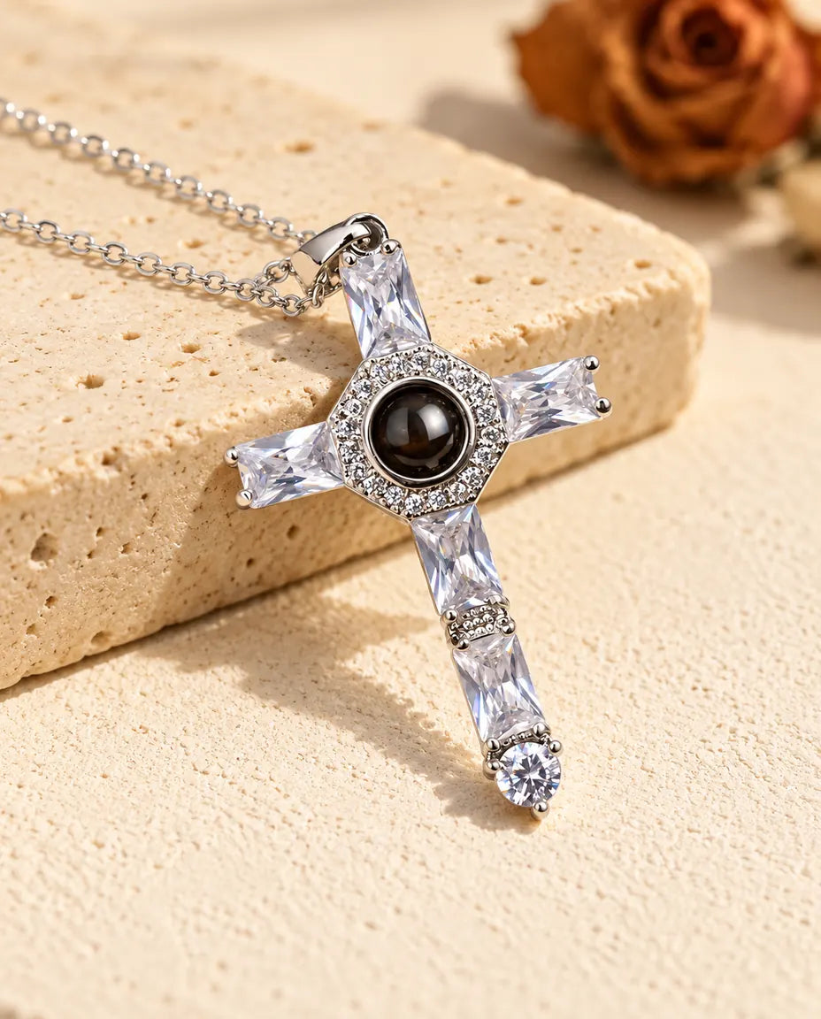 Silver tone cubic zirconia cross projection necklace lying against travertine