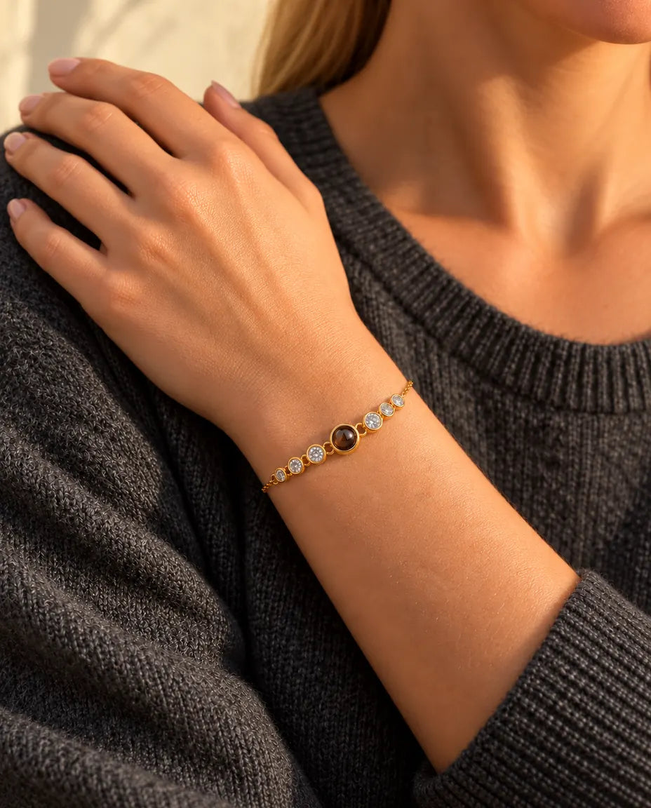 Close-up of the gold tone cubic zirconia projection bracelet on a wrist, her hand resting on her shoulder