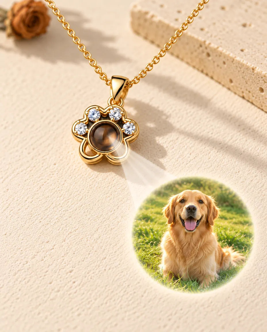 Gold tone paw print necklace projecting a golden retriever photo onto cream plaster
