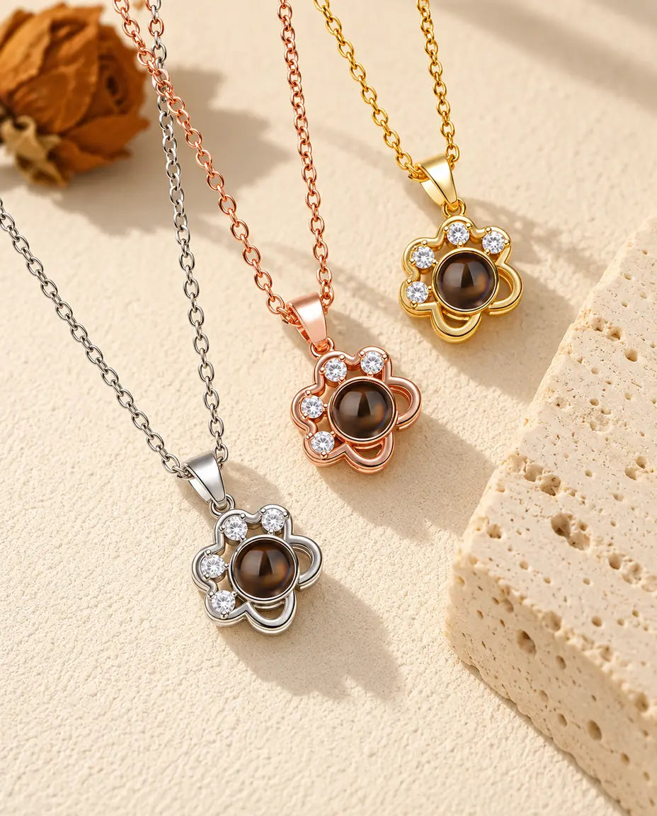 Three colours of the dainty paw print projection necklace beside a travertine block