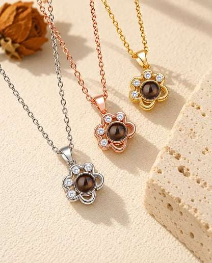 Three colours of the dainty paw print projection necklace beside a travertine block