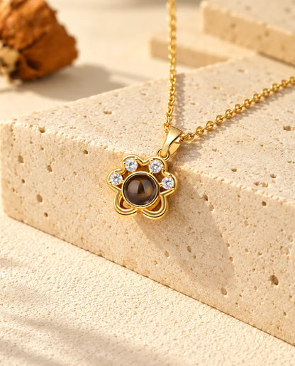 Gold tone paw print projection necklace hanging over travertine