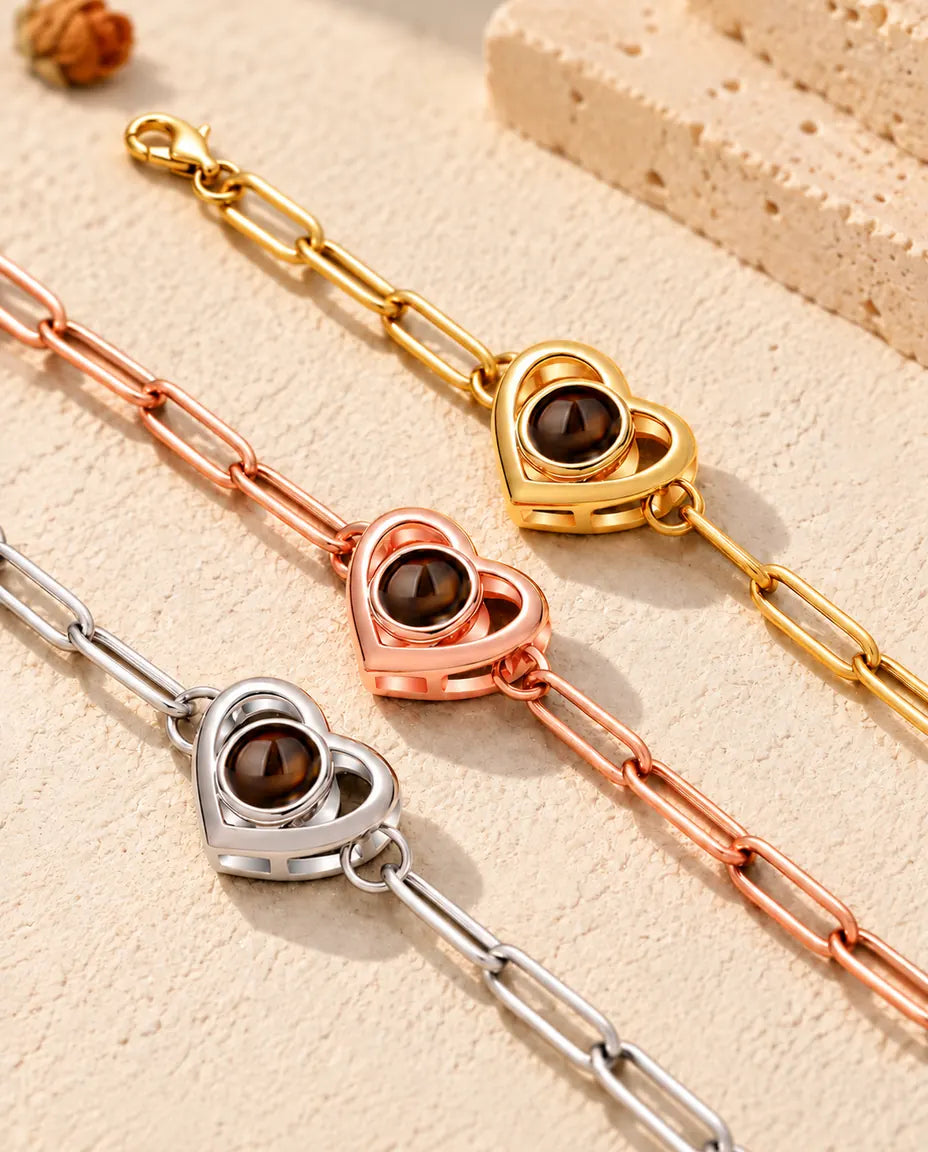 Close-up of three double heart projection bracelets in gold tone, rose gold tone and silver tone