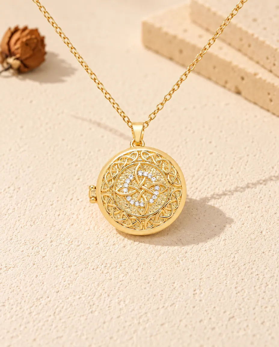 Front view of the gold tone round four-loop Celtic knot locket showing the lid design and side hinge