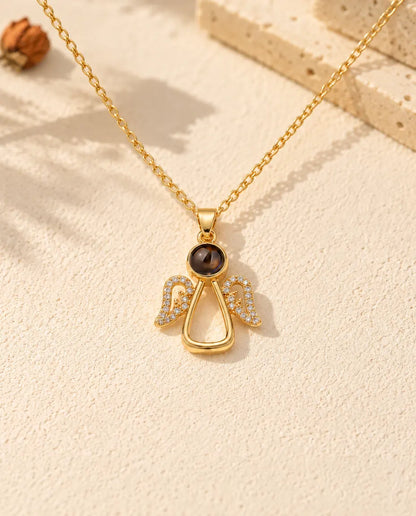 Front view of the gold tone angel pendant with the projection stone as its head