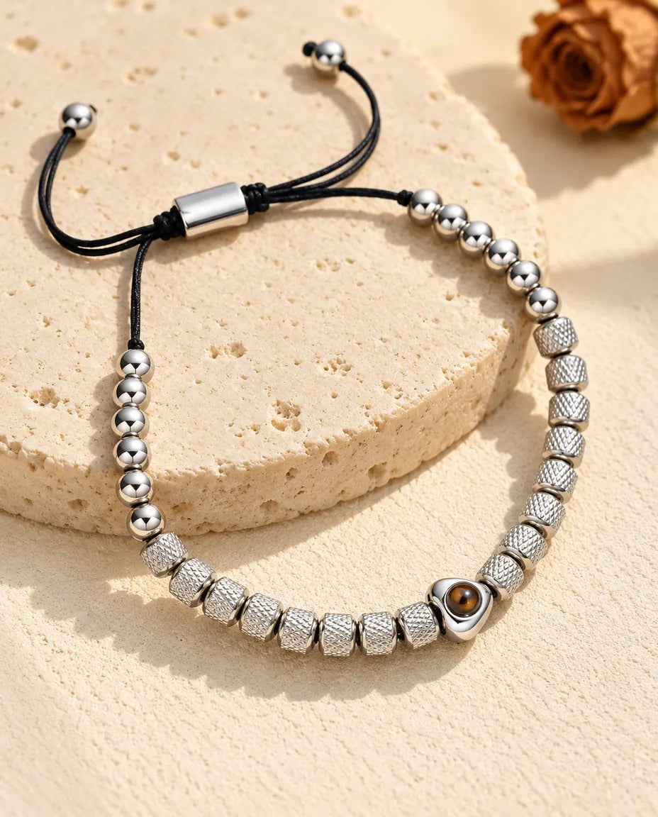 Personalised heart photo projection beaded bracelet in silver tone with textured barrel beads, on a travertine slab