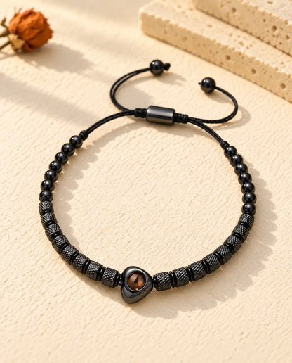 Top view of the black heart photo projection bead bracelet on cream plaster
