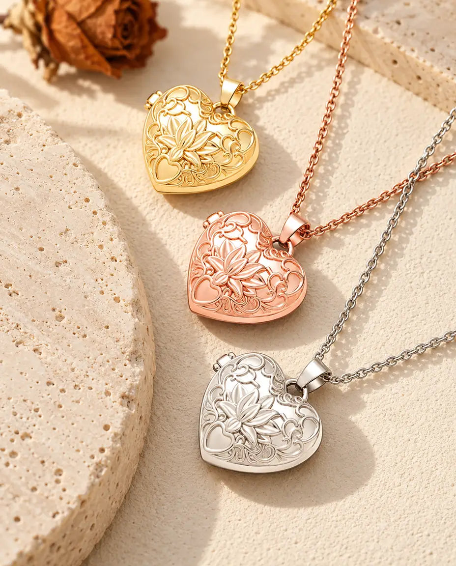 Gold tone, rose gold tone and silver tone lotus flower heart photo lockets stacked beside a travertine slab