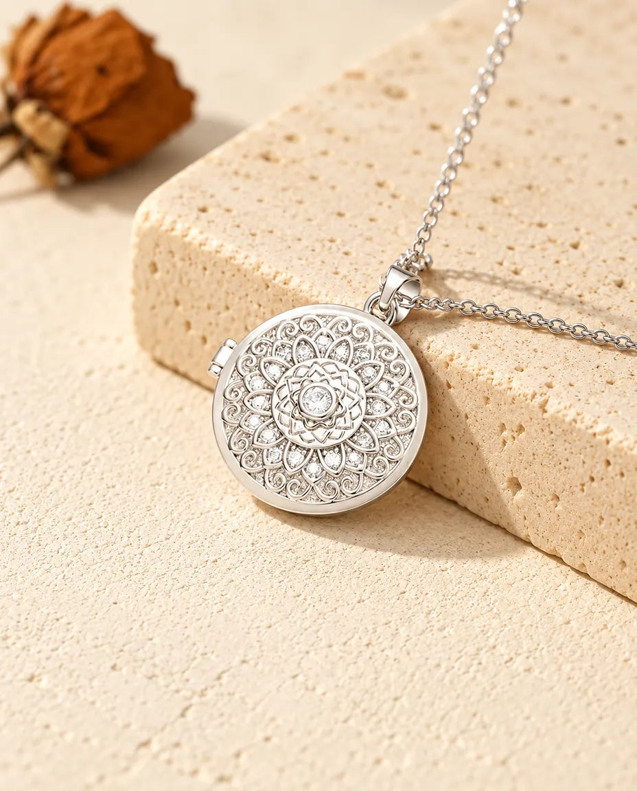 Personalised mandala flower photo locket necklace in silver tone with cubic zirconia petals, resting on a travertine block