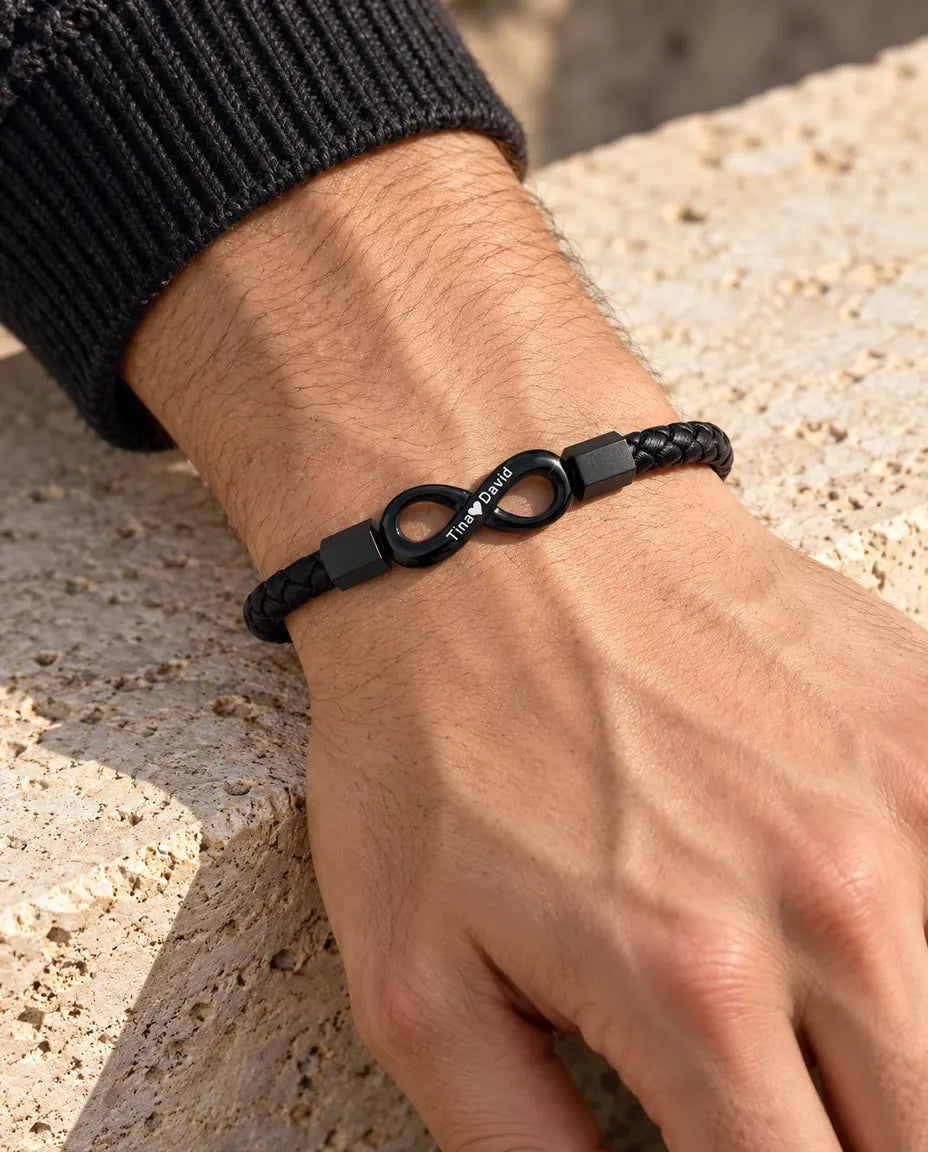 Man wearing the black engraved infinity faux leather bracelet on his wrist with a charcoal knit sweater