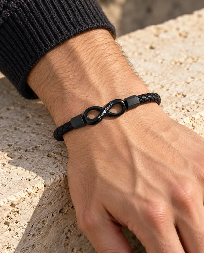 Man wearing the black engraved infinity faux leather bracelet on his wrist with a charcoal knit sweater