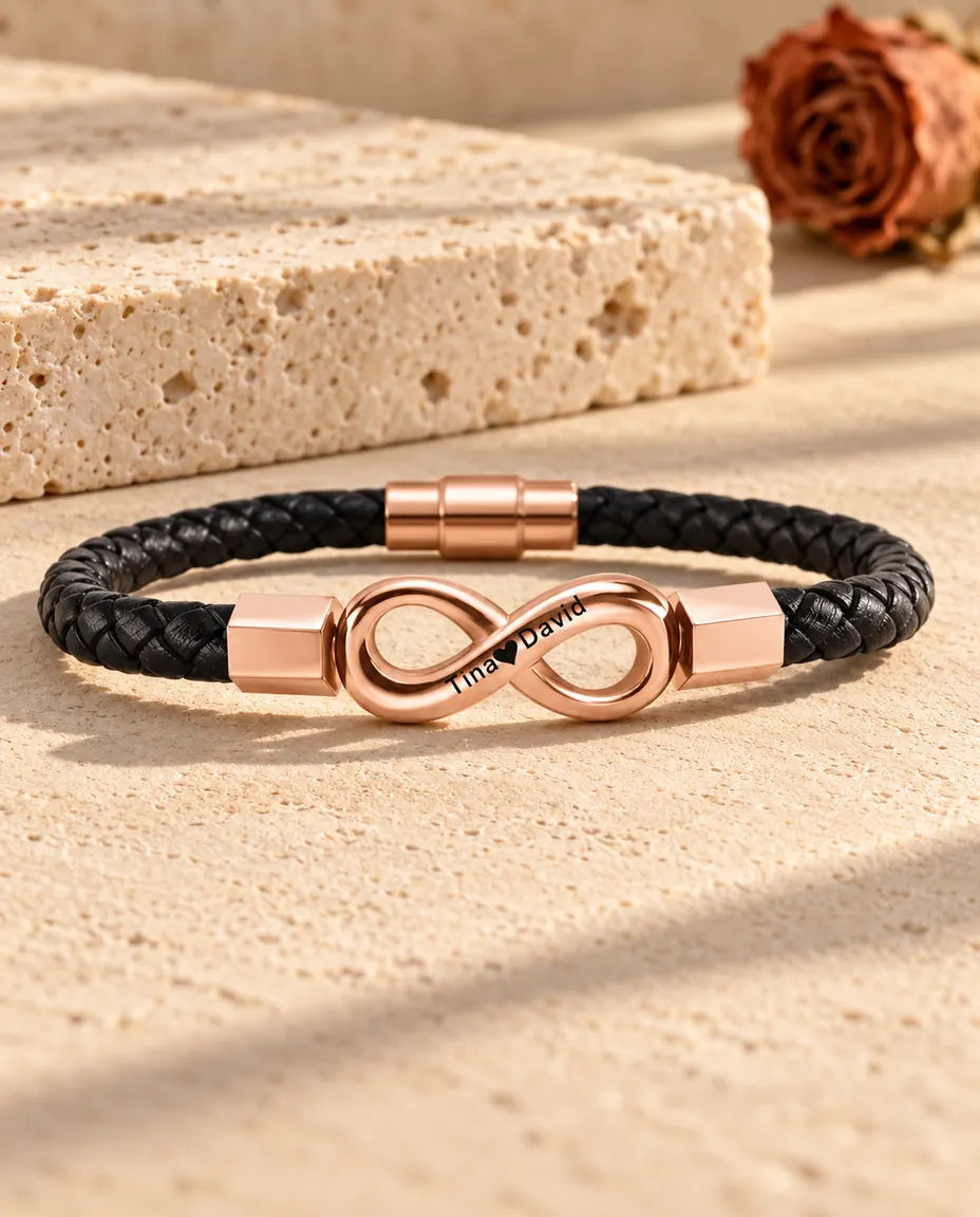 Rose gold tone engraved infinity link on a black braided faux leather bracelet