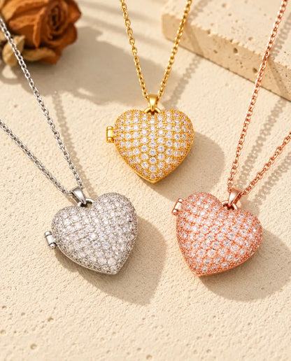 Three colours of the pave heart photo locket necklace arranged on plaster