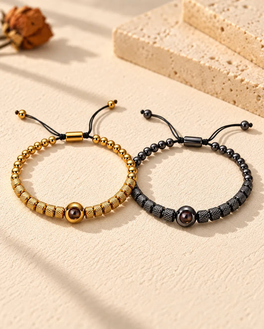 Personalised couples photo projection bracelets, a matching set of two textured bead bracelets in gold tone and black on cream plaster