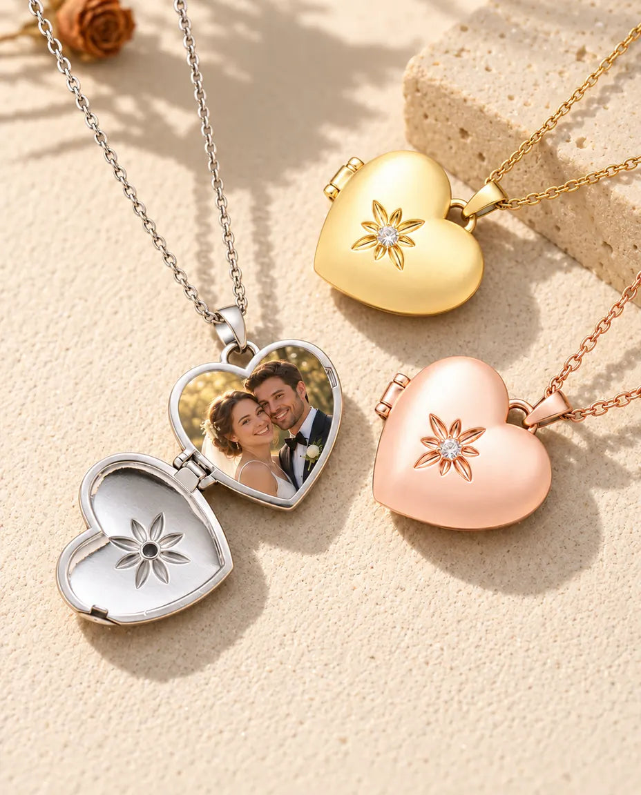 Silver tone satin flower heart photo locket opened to show a wedding photo inside, beside closed gold tone and rose gold tone lockets