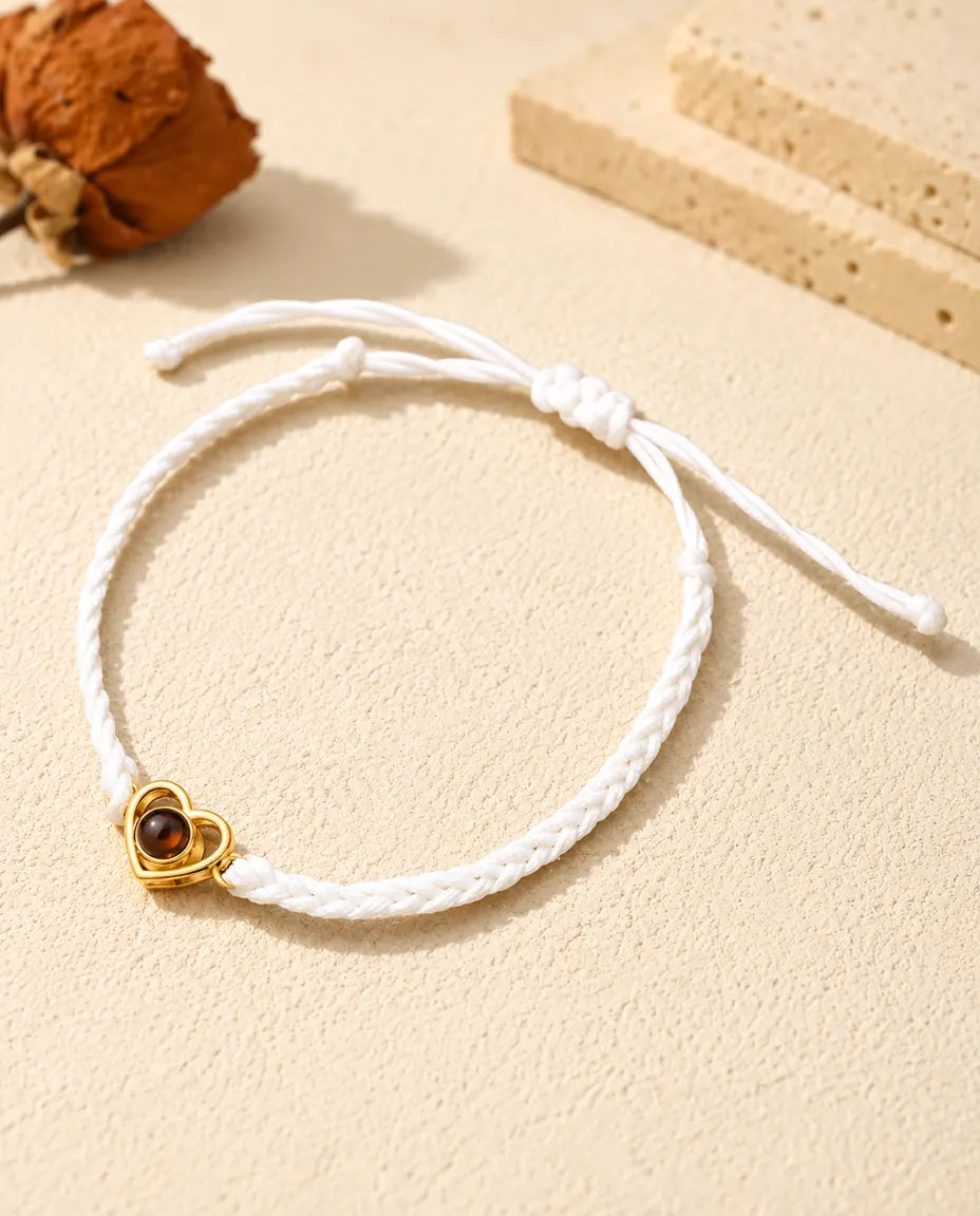 White braided cord photo projection bracelet with a gold tone open heart charm and sliding knot