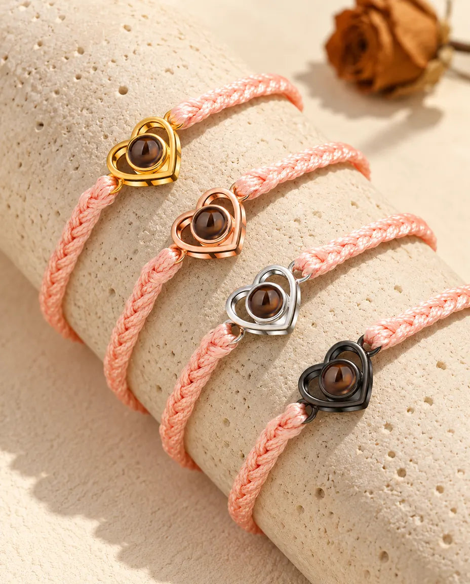 Pink braided cord open heart bracelets showing every charm colour draped over travertine