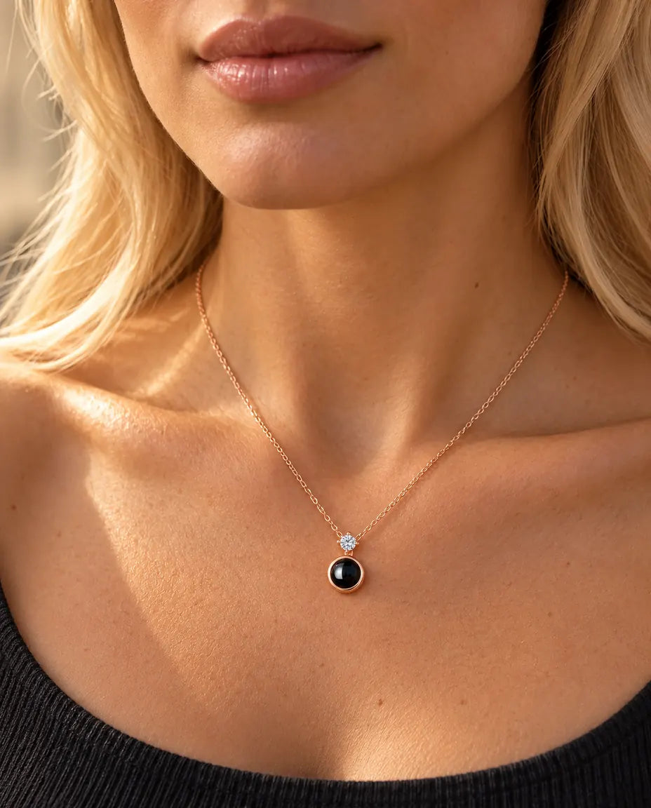 Woman in a charcoal top wearing the dainty rose gold tone solitaire projection necklace