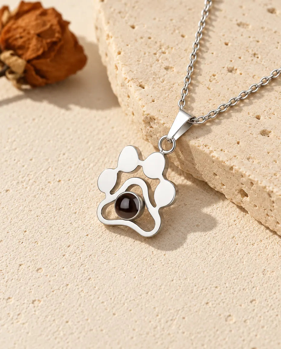 Personalised sterling silver paw print photo projection necklace on a travertine slab