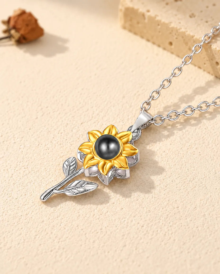 Sterling silver sunflower projection pendant with two leaves lying on plaster