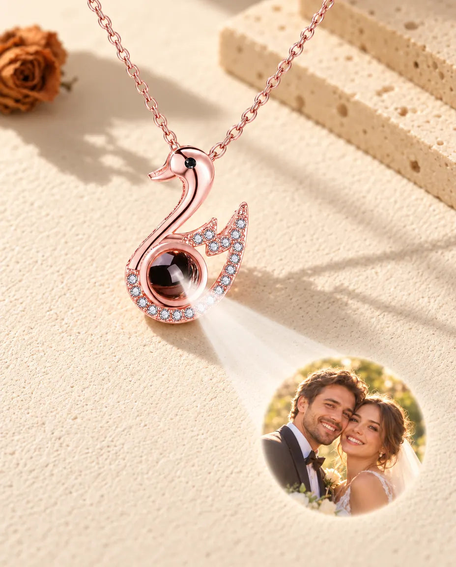 Rose gold tone swan necklace projecting a wedding photo onto cream plaster