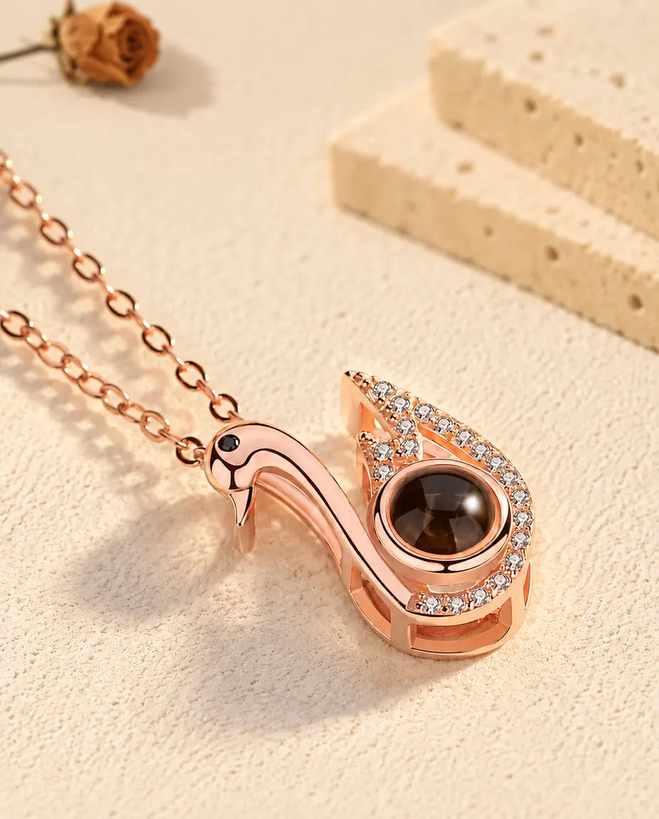 Rose gold tone swan projection pendant tilted on cream plaster