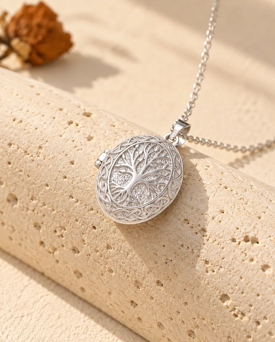 Personalised oval tree of life photo locket necklace in silver tone with a Celtic knot border, draped over a travertine block