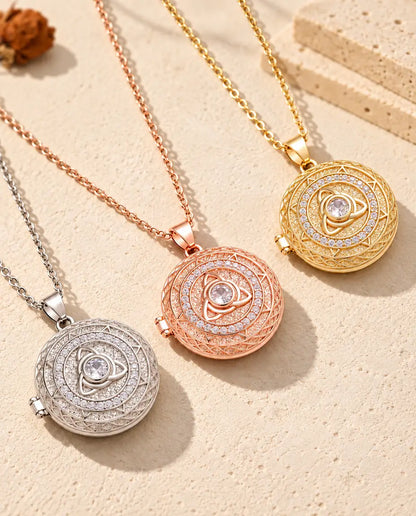 Trinity knot photo lockets in silver tone, rose gold tone and gold tone laid diagonally on cream plaster